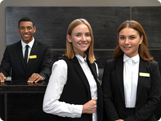 Two female hospitality staff in black and white uniforms smiling